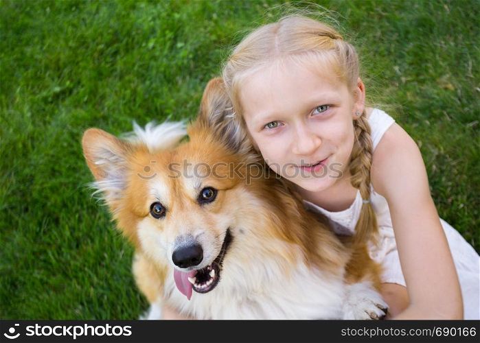 beautiful fun blond girl and corgi fluffy sit on the lawn
