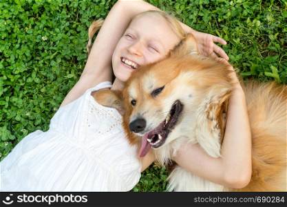 beautiful fun blond girl and corgi fluffy sit on the lawn