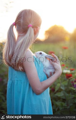 beautiful fun blond girl and rabbit on a sunny summer day