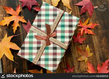 Beautiful gift with fall leaves on a wooden rustic background