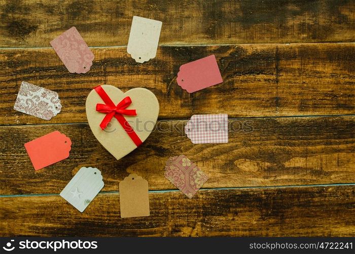 Beautiful gift with heart shape and red ribbon on a wooden background