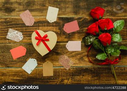 Beautiful gift with heart shape and red ribbon on a wooden background