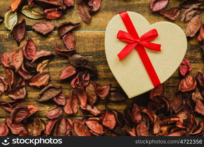 Beautiful gift with red ribbon around dry petals