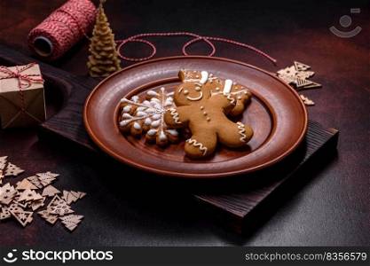 Beautiful gingerbread on a brown ceramic plate with Christmas tree decorations on a dark concrete background. Getting home ready for Christmas. Beautiful gingerbread on a brown ceramic plate with Christmas tree decorations on a dark concrete background
