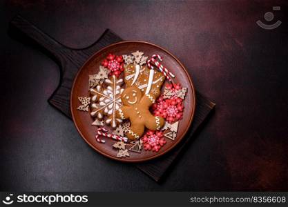 Beautiful gingerbread on a brown ceramic plate with Christmas tree decorations on a dark concrete background. Getting home ready for Christmas. Beautiful gingerbread on a brown ceramic plate with Christmas tree decorations on a dark concrete background