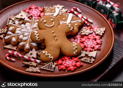 Beautiful gingerbread on a brown ceramic plate with Christmas tree decorations on a dark concrete background. Getting home ready for Christmas. Beautiful gingerbread on a brown ceramic plate with Christmas tree decorations on a dark concrete background