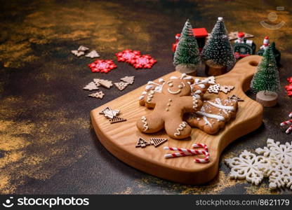 Beautiful gingerbread on a brown ceramic plate with Christmas tree decorations on a dark concrete background. Getting home ready for Christmas. Beautiful gingerbread on a brown ceramic plate with Christmas tree decorations