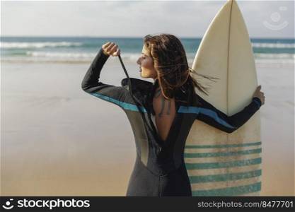 Beautiful girl at the beach wearing a surf wetsuit