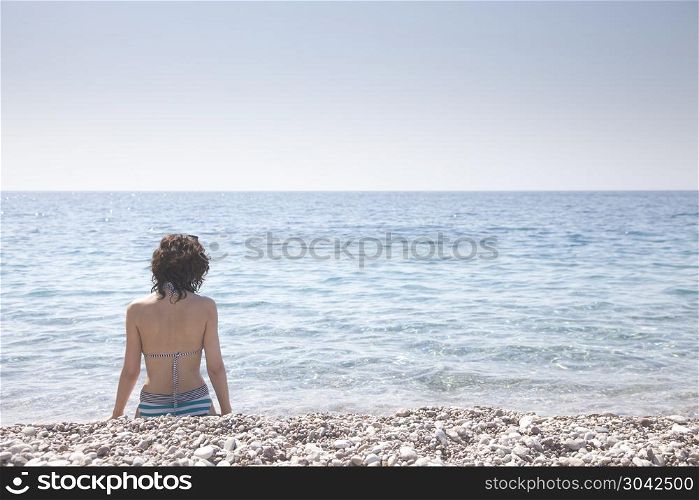 Beautiful girl bathed in sunshine sitting on the beach. Beautiful girl bathed in sunshine.