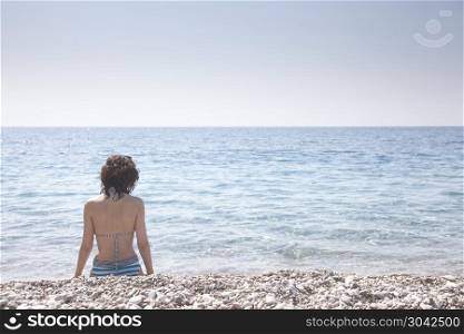 Beautiful girl bathed in sunshine sitting on the beach. Beautiful girl bathed in sunshine.