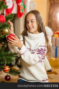 Beautiful girl decorating Christmas tree at living room