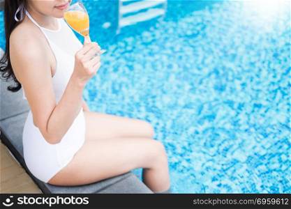 Beautiful girl drinking cosmopolitan cocktail, lying swimming pool, summer vacation concept