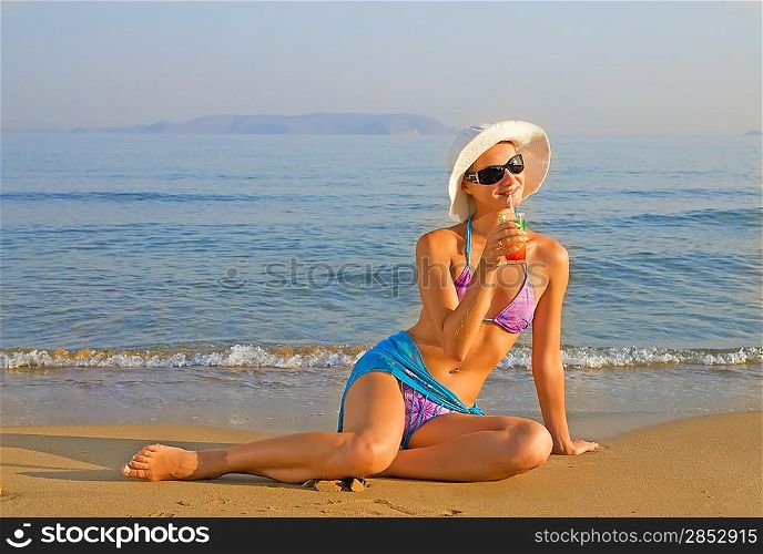 Beautiful girl drinking fruit cocktail on the beach