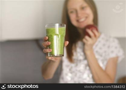 Beautiful girl drinks freshly prepared smoothie in kitchen. smoothies freshly made from assorted vegetable ingredients on kitchen counter. Healthy Eating. selective focus.. Beautiful girl drinks freshly prepared smoothie in kitchen. smoothies freshly made from assorted vegetable ingredients on kitchen counter. Healthy Eating. selective focus