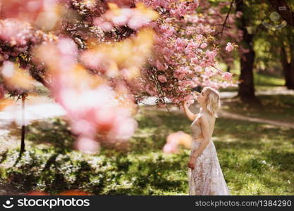 beautiful girl enjoys the scent of flowering tree. Portrait of beautiful woman with blooming cherry tree - girl inhales the scent of flowers with closed eyes - spring, nature and beauty concept.. beautiful girl enjoys the scent of flowering tree. Portrait of beautiful woman with blooming cherry tree - girl inhales the scent of flowers with closed eyes - spring, nature and beauty concept