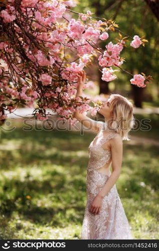 beautiful girl enjoys the scent of flowering tree. Portrait of beautiful woman with blooming cherry tree - girl inhales the scent of flowers with closed eyes - spring, nature and beauty concept. beautiful girl enjoys the scent of flowering tree. Portrait of beautiful woman with blooming cherry tree - girl inhales the scent of flowers with closed eyes - spring, nature and beauty concept.
