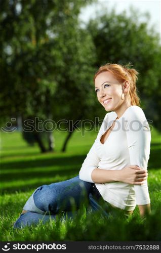 Beautiful girl having a rest on a lawn in park
