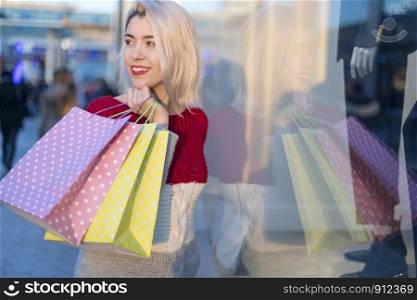 Beautiful girl holding shopping bags, looking at camera and smiling