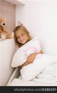 Beautiful girl hugs a pillow on the bed in the nursery