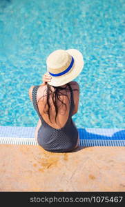 Beautiful girl in a black swimsuit near a blue pool.. Beautiful girl in a black swimsuit near a blue pool