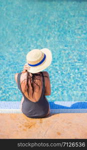 Beautiful girl in a black swimsuit near a blue pool.. Beautiful girl in a black swimsuit near a blue pool