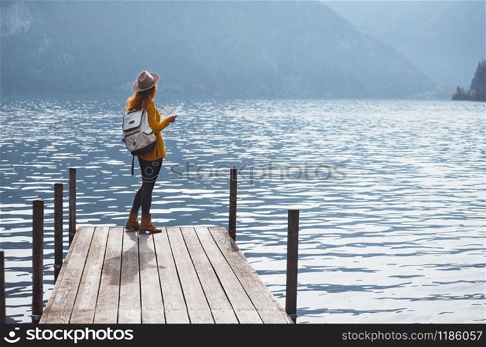 beautiful girl in a hat on the pier at the lake bank and mountains in the background
