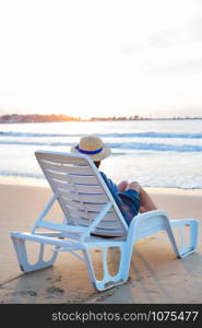 Beautiful girl in a hat sits on a deckchair meeting the dawn.. Beautiful girl in a hat sits on a deckchair meeting the dawn