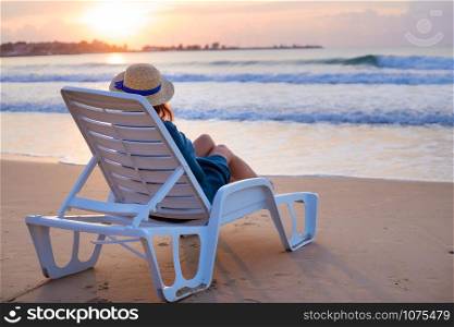 Beautiful girl in a hat sits on a deckchair meeting the dawn.. Beautiful girl in a hat sits on a deckchair meeting the dawn