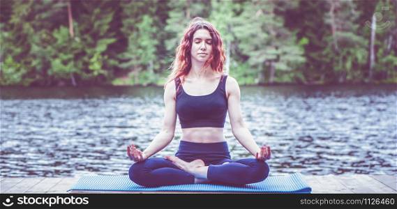 Beautiful girl in a yoga pose on the lake. Lotus position , Padmasana. The concept of appeasement, healthy lifestyle. Panoramic view
