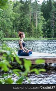 Beautiful girl in a yoga pose on the lake. Lotus position ,  Padmasana. The concept of appeasement,  healthy lifestyle. Panoramic view