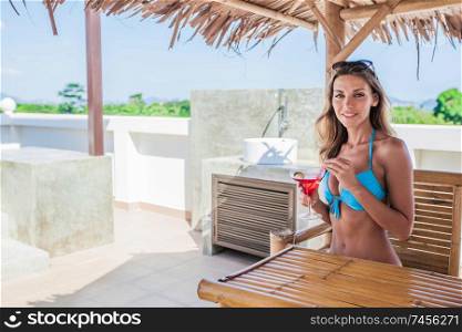 Beautiful girl in bikini drinking a cocktail at tourist resort cafe. Girl drinking a cocktail