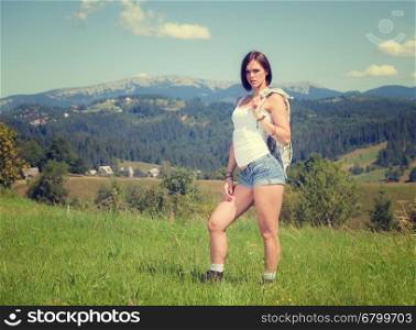 Beautiful girl in country style clothes standing at grass meadow