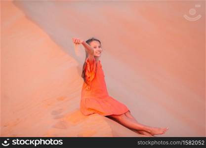 Beautiful girl in red dress on vacation in dunes in beautiful desert. Girl among dunes in Rub al-Khali desert in United Arab Emirates
