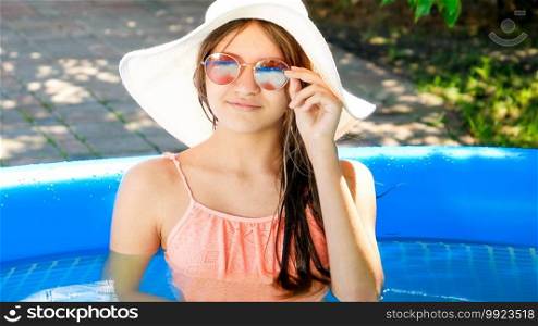 Beautiful girl in sunglasses and hat relaxing in swimming pool.. Beautiful girl in sunglasses and hat relaxing in swimming pool