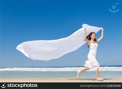 Beautiful girl in the beach running and holding a white piece of fabric