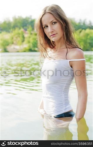 Beautiful girl in wet t-shirt stands waist-deep in water.