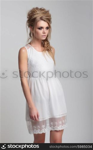 Beautiful girl in white dress goes on a light background.