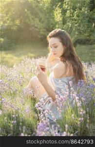 Beautiful girl is drinking  wine in lavender field