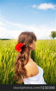 Beautiful girl is standing with her back in a white dress in a wheat field.. Beautiful girl is standing with her back in a white dress in a wheat field