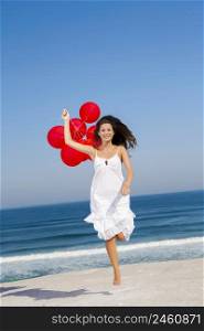 Beautiful girl jumping with red ballons in the beach