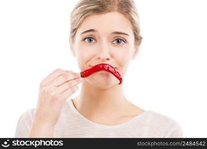 Beautiful girl making a sad face with a red chilli pepper in front of the mouth, isolated over a white background