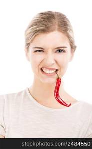 Beautiful girl making a silly face biting a red chilli pepper, isolated over a white background