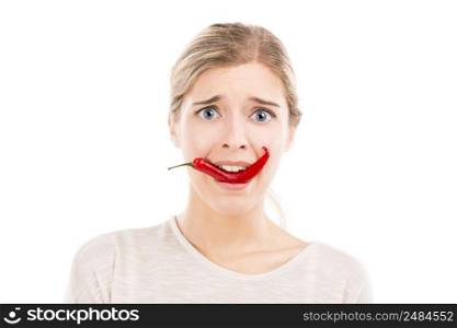 Beautiful girl making a silly face biting a red chilli pepper, isolated over a white background