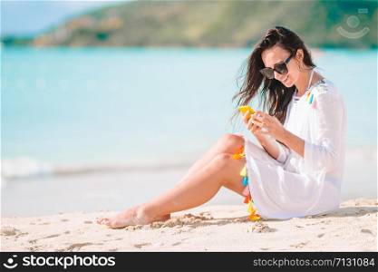Beautiful girl on the beach with cellphone on caribbean island. Young woman with smartphone during tropical beach vacation.