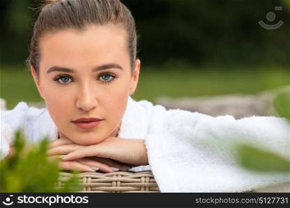 Beautiful girl or young woman relaxing in robe outside at health spa