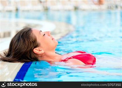 beautiful girl relaxes in the pool with your eyes closed