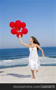 Beautiful girl running with red ballons in the beach
