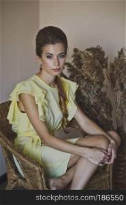 Beautiful girl sitting in a chair.. A woman in a long yellow dress 4928.