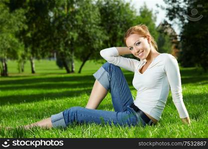 Beautiful girl sitting on a lawn in a summer garden
