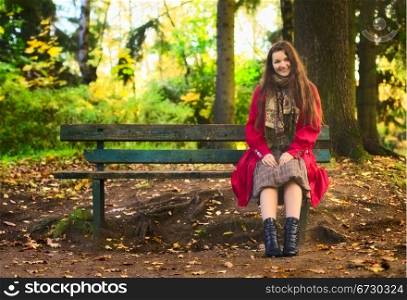 beautiful girl sitting on bench in enchanted autumn park